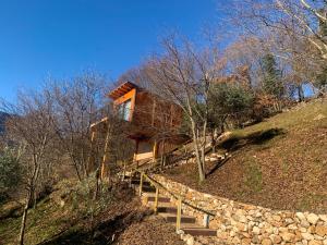 a house on top of a hill with a stone wall at Tree House San Giorgio in Solagna