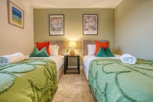 a bedroom with two beds with green and orange pillows at Ashcroft Loft by Apricity Property - Stunning 3 Bedroom, 2 bathrooms, Cosy Central Apartment with balcony in Cirencester