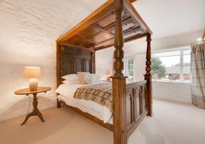 a bedroom with a canopy bed and a table at The Shippons in Abersoch