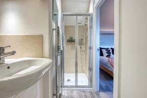 uma casa de banho com um lavatório e um chuveiro em Ashcroft Loft by Apricity Property - Stunning 3 Bedroom, 2 bathrooms, Cosy Central Apartment with balcony em Cirencester