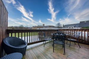 a deck with a table and chairs on a balcony at Ashcroft Loft by Apricity Property - Stunning 3 Bedroom, 2 bathrooms, Cosy Central Apartment with balcony in Cirencester