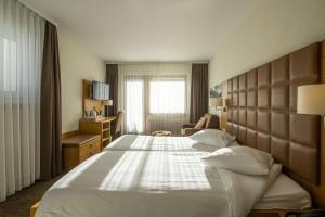 una camera d'albergo con un letto grande e una sedia di Hotel Olympic - Montana Center a Crans-Montana