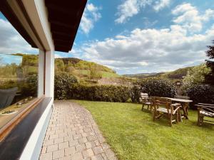 a patio with a table and chairs on the grass at Ferienhaus Rothaarblick in Schmallenberg