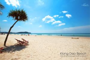 a beach with two beach chairs and a palm tree at Lemonade Boutique Inn in Ko Lanta