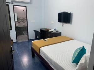 - une chambre avec un lit, un bureau et une télévision dans l'établissement Elite Inn, à Pondichéry