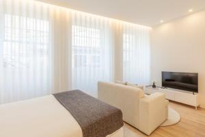 a white bedroom with a bed and a television at Boavista Collection Studio - Minho's Guest in Braga