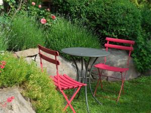 2 chaises rouges et une table dans un jardin dans l'établissement Ferienwohnung Lanz 2, à Lana