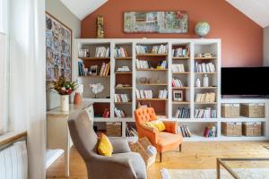- un salon avec des murs orange et des bibliothèques blanches dans l'établissement Maison pour 8 avec piscine - Noirmoutier-en-l'Île, à Noirmoutier-en-l'lle