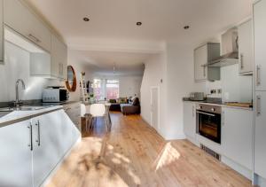 a kitchen with white cabinets and a wooden floor at Pontcanna Mews in Cardiff