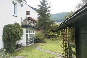 uma casa branca com um portão e um jardim em Weitblick auf Berg, Wald und Wiese em Schmallenberg