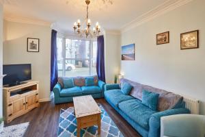 uma sala de estar com sofás azuis e uma televisão em Host & Stay - Holyrood Lodge em Bridlington