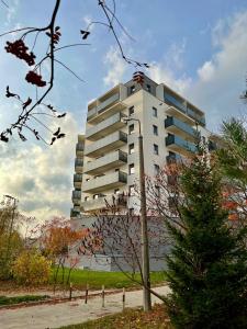 un grand bâtiment blanc avec un arbre devant lui dans l'établissement ApartamentySnu, Struga Tower Gold z parkingiem, à Radom