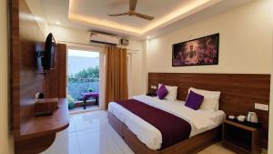 a bedroom with a bed with purple pillows and a window at Perfectstayz Value Forest Valley Near Waterfall in Rishīkesh +70 photos