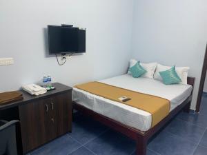 - une chambre avec un lit et une télévision murale dans l'établissement Elite Inn, à Pondichéry
