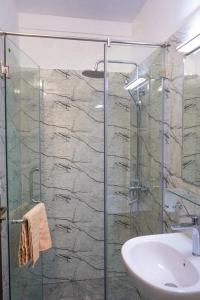 y baño con ducha acristalada y lavamanos. en Vista Apartment Mariners Blue en Nuwara Eliya