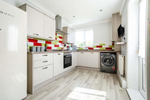 a kitchen with white cabinets and a washer and dryer at Beautiful 3 bedroom home, 10 minutes walk to Beach. in Cleethorpes