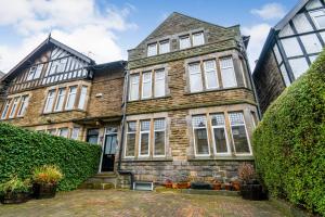 an old brick house with white windows and bushes at Spacious Victorian Townhouse near HCC with off street parking in Harrogate