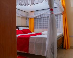 1 dormitorio con 1 cama con sábanas rojas y blancas en Cassabella Apartment, Opposite Metropark Hotel en Kisumu