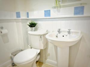 Baño blanco con aseo y lavamanos en Davis House - 6 Beds, Sleeps up to 7, en Rothwell