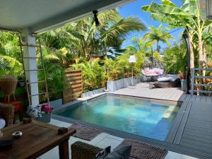 - une piscine dans un jardin planté de palmiers dans l'établissement Home sweet home, à Saint-Gilles les Bains