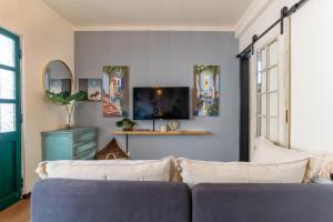 a living room with a couch and a tv at Arty Vintage Townhouse with Rooftop Shower & Sun Loungers in Olhão