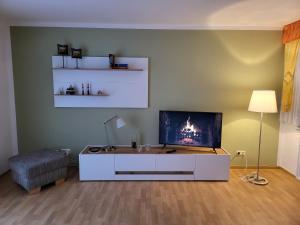a living room with a tv and a white cabinet at Haus Nutheblick - Komfort Appartement in Trebbin