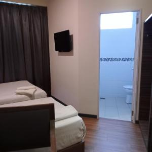 a room with two beds and a bathroom with a television at Hotel 138 @ Bestari in Shah Alam