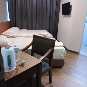 a hotel room with two beds and a table and chair at Hotel 138 @ Bestari in Shah Alam