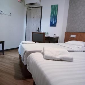 Habitación con 3 camas con sábanas blancas y escritorio. en Hotel 138 @ Bestari, en Shah Alam