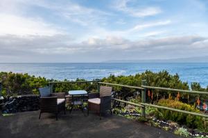 a table and chairs on a balcony overlooking the ocean at Casa do Caramba - The Dream House in São Roque do Pico