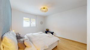 - une chambre blanche avec un lit et une fenêtre dans l'établissement Sublime modern family apartment of 2 bedrooms, à Loèche-les-Bains