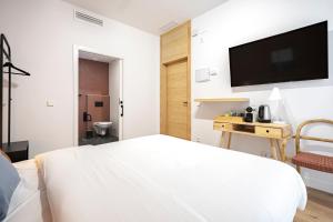 sypialnia z białym łóżkiem i telewizorem z płaskim ekranem w obiekcie Vallecas Suites by Olala Homes w Madrycie +37 zdjęć