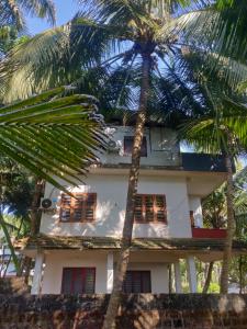a white house with palm trees in front of it at Sunshine Service Villa in Kannur