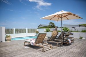 a patio with two chairs and an umbrella and a table at Ocean Mist in Plettenberg Bay