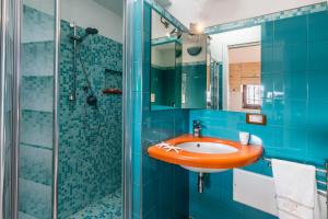 bagno blu con lavandino e doccia di Appartamento Corallo - MyHo Casa a Torre Canne