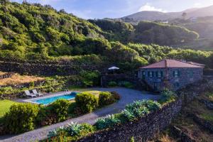 una vista aérea de una casa con piscina y montaña en Stone Home Casa do Caisinho Pico island en Terra Alta