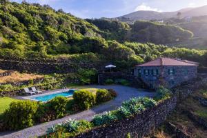 an aerial view of a house with a swimming pool and a mountain at Stone Home Casa do Caisinho Pico island in Terra Alta