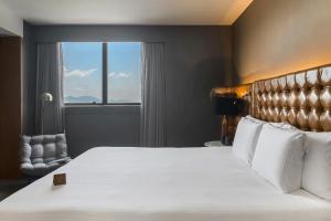 a bedroom with a large bed with a large window at Pullman Sao Paulo Guarulhos Airport in Guarulhos