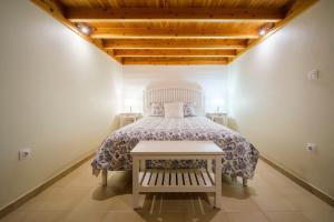 a bedroom with a bed with a white bedspread at Stone Home Casa do Caisinho Pico island in Terra Alta