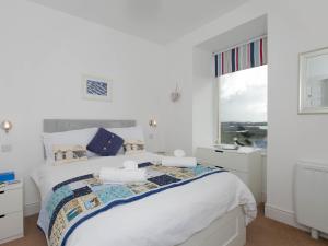 a white bedroom with a bed and a window at Pass the Keys Modern 2 Bedroom Apartment with stunning Sea Views in Trearddur