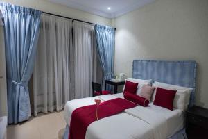 a bedroom with a large white bed with red pillows at The Ritzz Exclusive Guest House in Accra