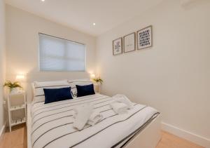 a white bedroom with a large bed with blue pillows at Sea Breeze in Newton