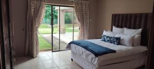 a bedroom with a bed and a sliding glass door at 3 Schnehage Guesthouse in Welkom