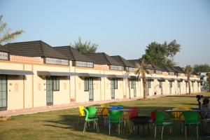 a row of buildings with tables and chairs in the grass at CLUB 21 by Sariska Fun City, Alwar in Mācheri