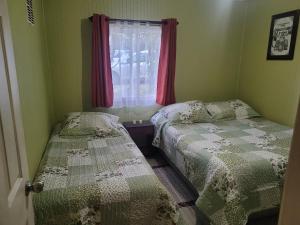 two beds in a small room with a window at Cabañas Tepual in Puerto Montt