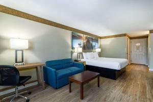 a hotel room with a bed and a blue chair at Days Inn by Wyndham Mountain Home in Mountain Home