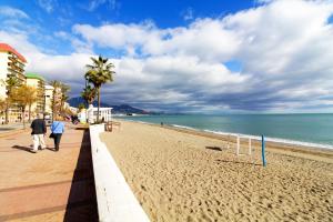 a beach with two people walking on the sand at JACINTO 2 Playa Fuengirola in Fuengirola