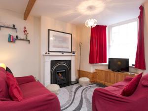 a living room with a fireplace and a red couch at Pass the Keys Comfortable Stone Built Cottage in Menai Bridge in Menai Bridge