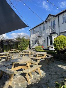 un grupo de mesas de picnic de madera frente a un edificio en The Sea Trout Inn, en Totnes