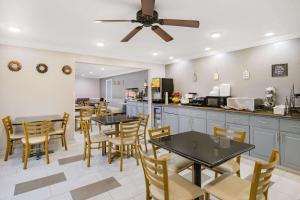 a dining room with tables and chairs and a kitchen at Baymont by Wyndham Gurnee in Gurnee